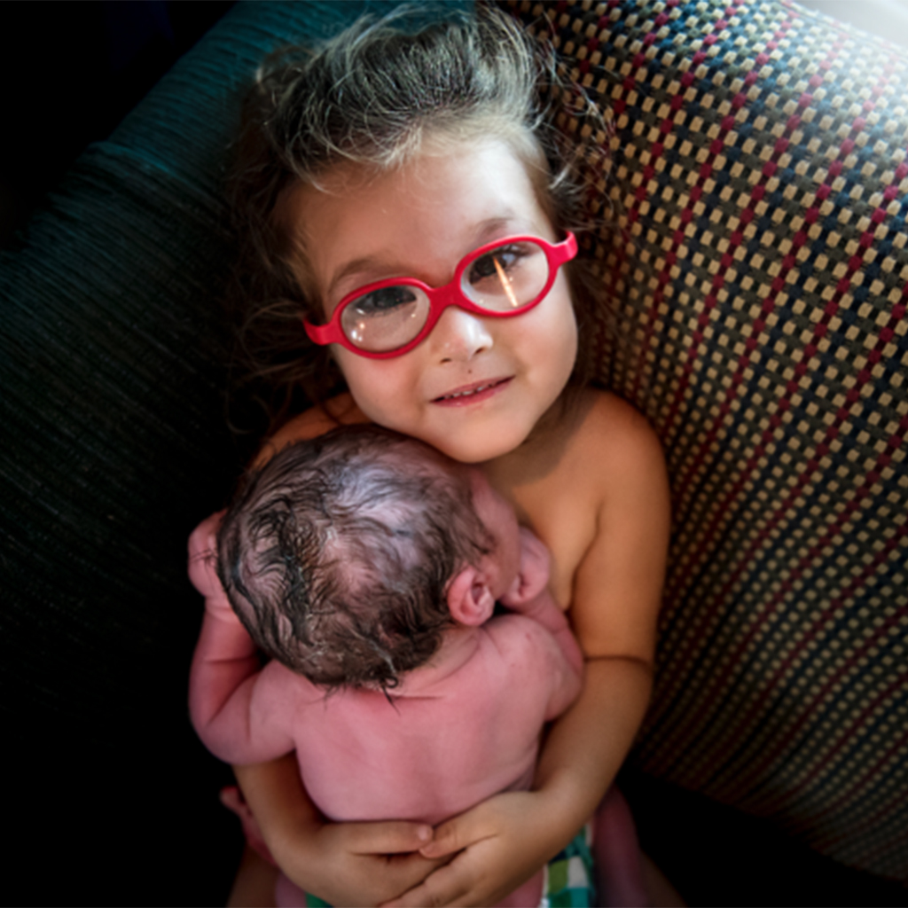 Three-year-old assists in the delivery of Baby Brother and embraces him with skin-to-skin contact.