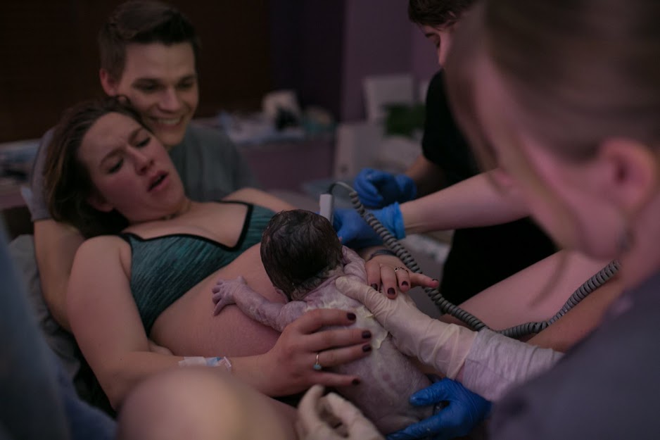 An emotional moment of a young mother welcoming twins is captured by a photographer.