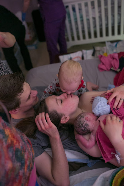 An emotional moment of a young mother welcoming twins is captured by a photographer.