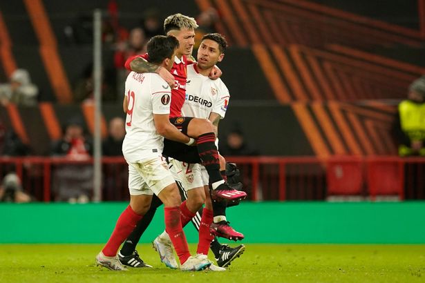 Sevilla's Marcos Acuna, left, and Sevilla's Gonzalo Montiel, right, help Manchester United's Lisandro Martinez off the pitch