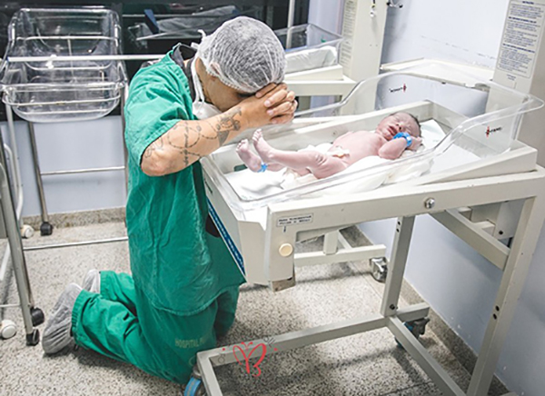 Internet melts over image of young Father Kneeling in prayer by his newborn