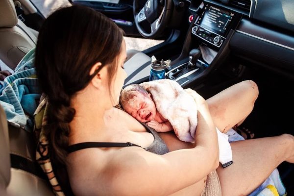 A woman gives birth unexpectedly while traveling to the birth center in a car.